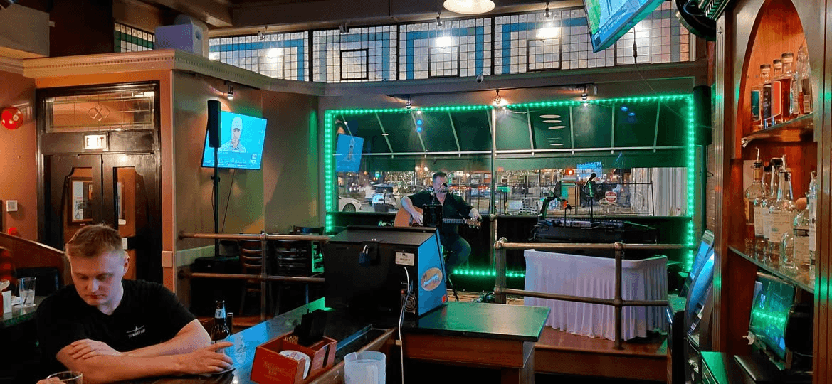 Live musician performing at Pearly Baker's Alehouse with historic stained glass transoms